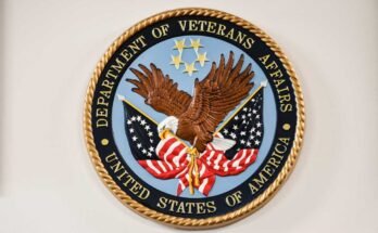 Un logotipo del Departamento de Veteranos estadounidenses, que tiene una Pygargue de cabeza blanca que aprieta una bandera de Betsy Ross y una bandera estadounidense.